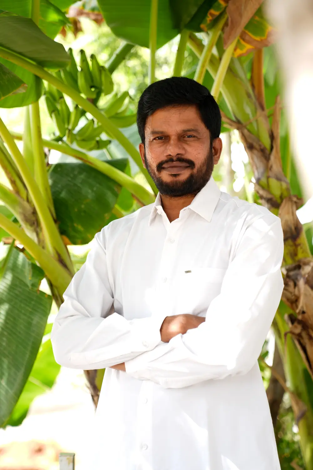 Dr. Krishna, BNYS among the banana plants outside the clinic